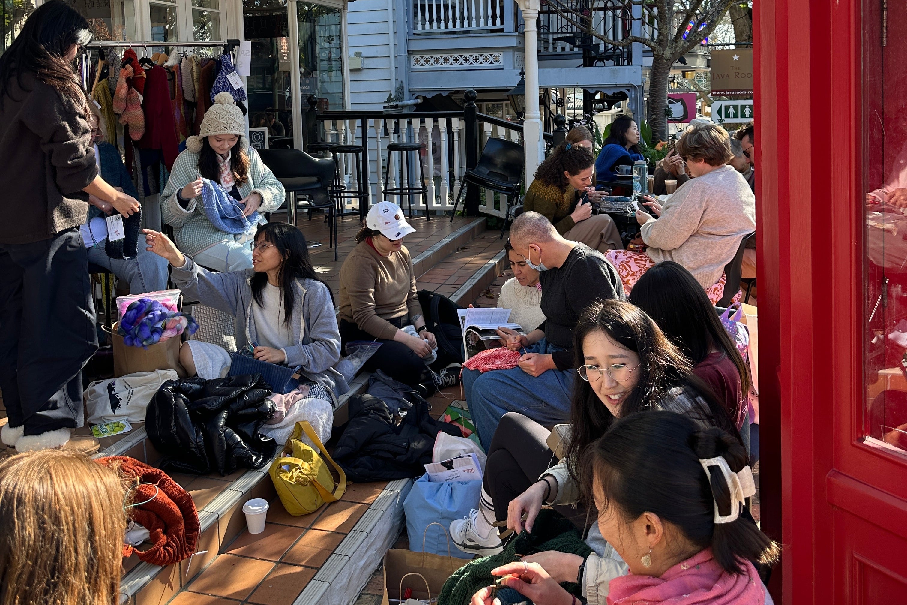 knitters gathered behind red Phone booth enjoying knitting, chatting and the sunshine on a fresh winters day